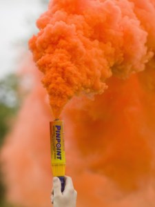 ashley-cooper-hand-holding-an-emergency-flare-with-orange-colored-smoke